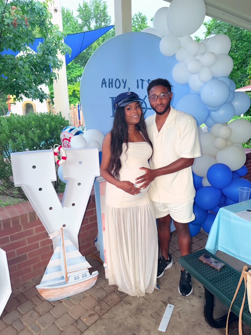 Couple posing at Ahoy It's a Boy nautical baby shower with balloon arch and sailboat prop
