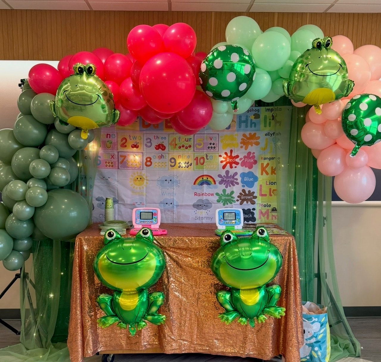 Frog themed party with balloon arch and educational backdrop